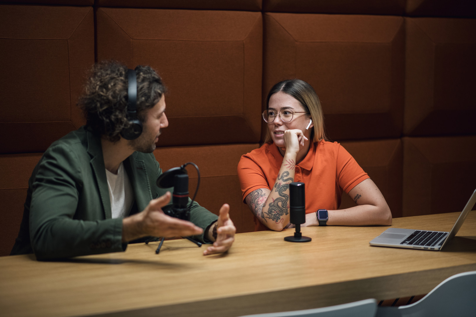 Two people speaking inside a recording booth