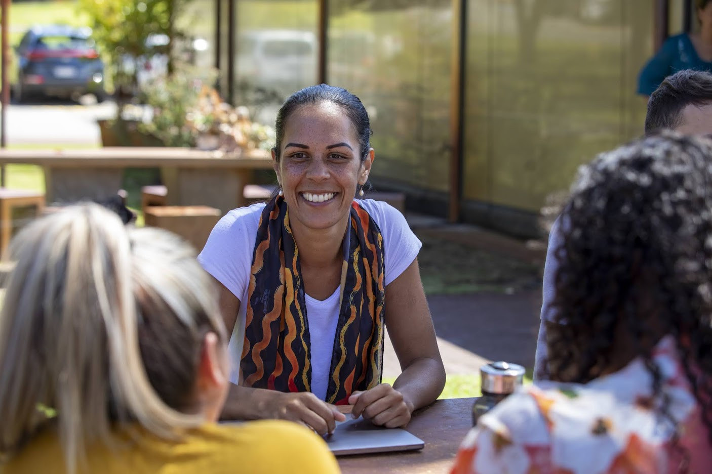 Woman smiling at table with friends.