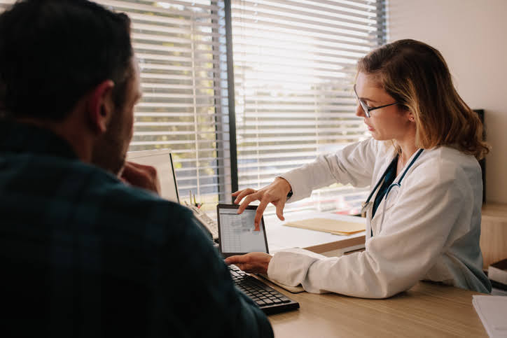 Doctor showing patient something on tablet screen.