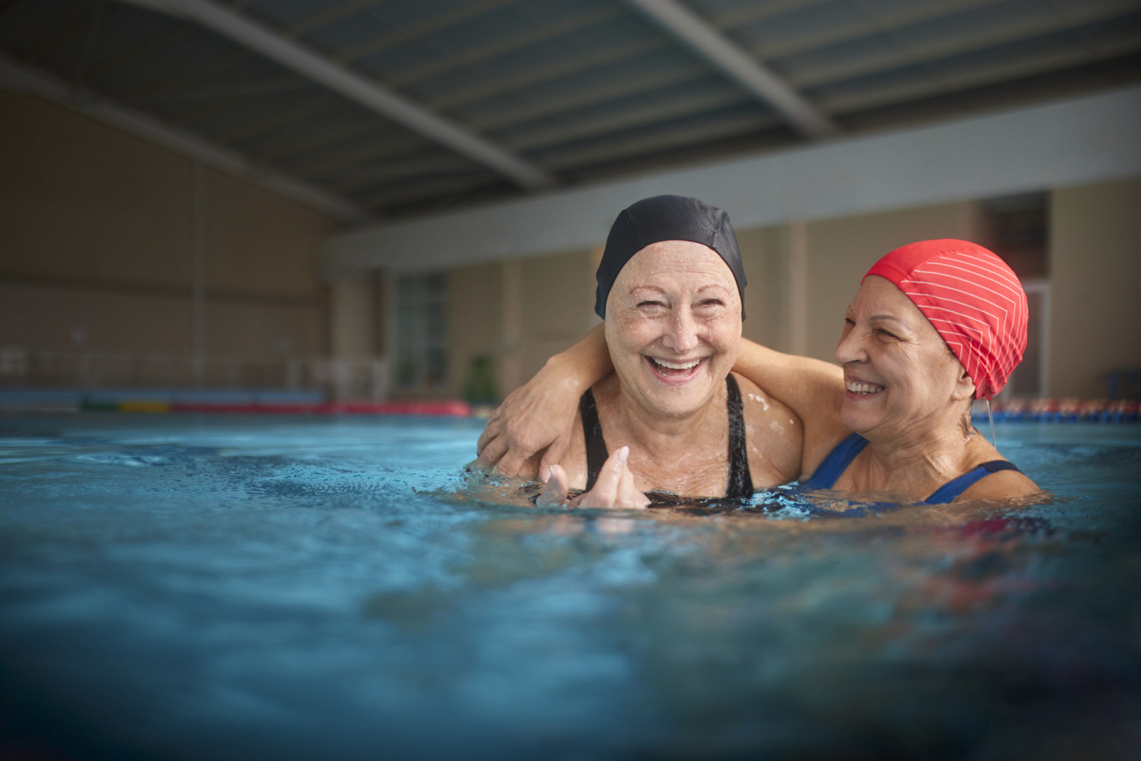Two older women smiling whilst doing swim aerobics 