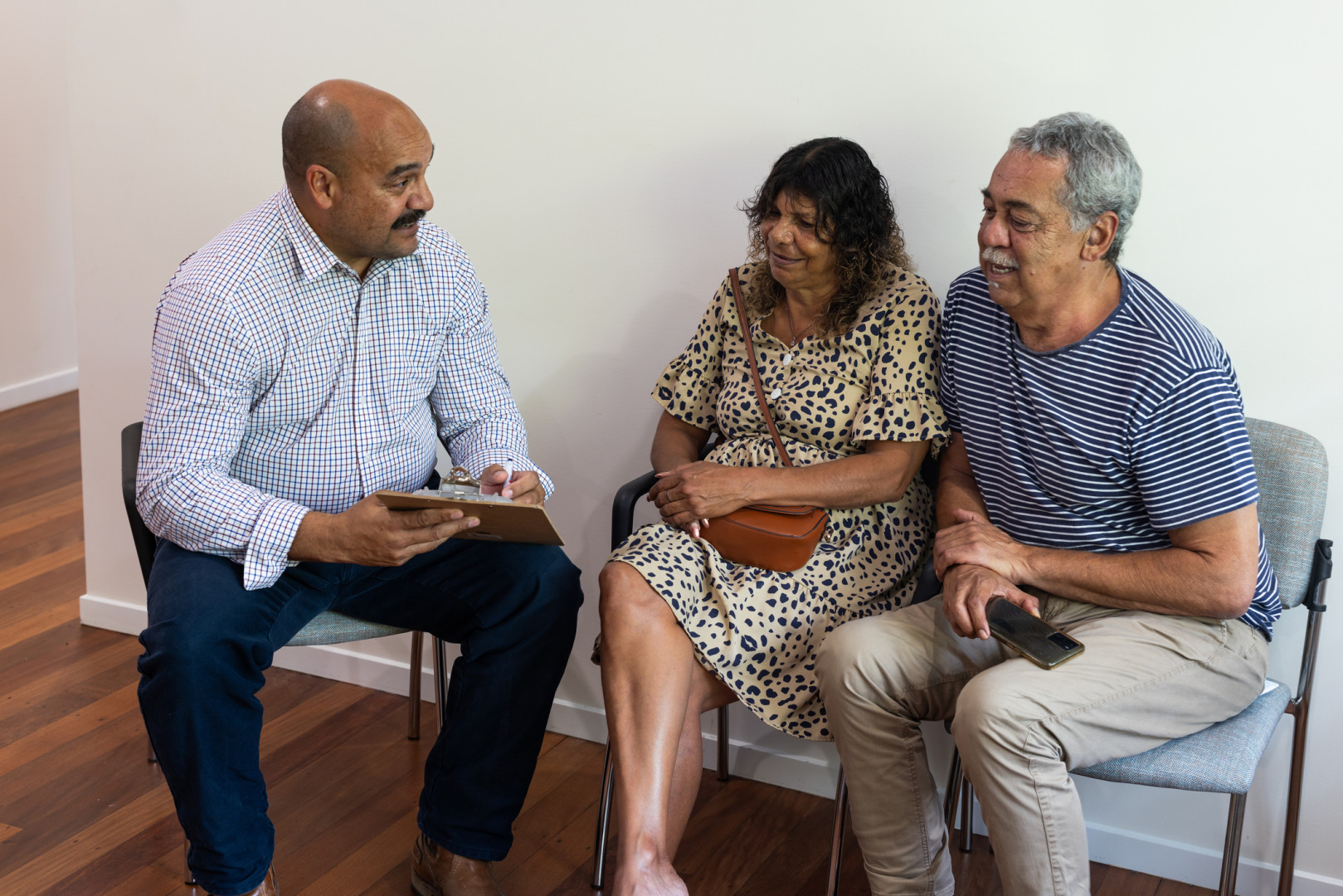 GP smiling whilst speaking with two Aboriginal patients.
