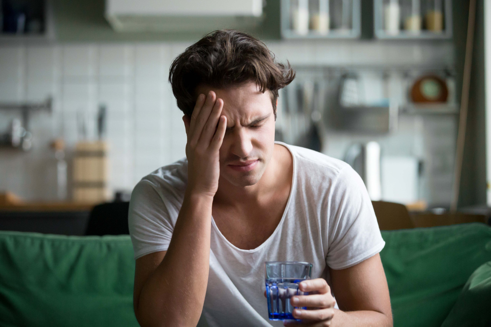 Man sitting on a couch with a glass of water